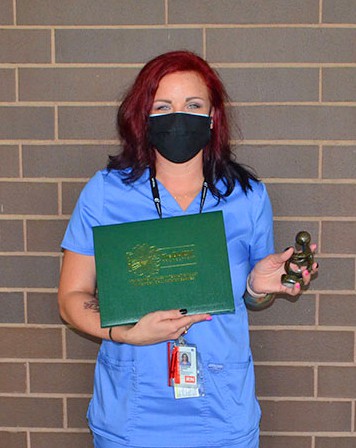 Nurse in blue smock with award