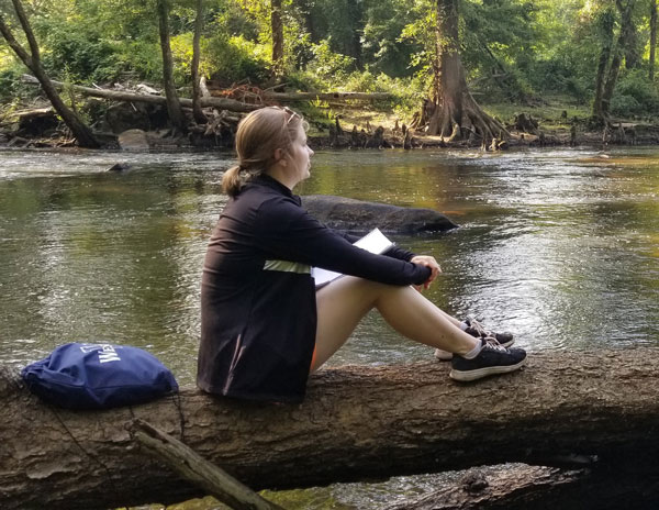 student looking at nature next to river