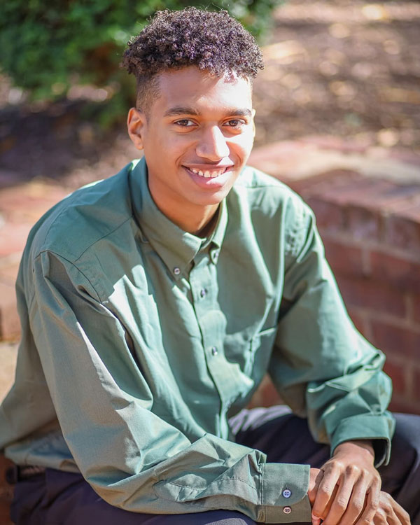 Black male student posing with green shirt on