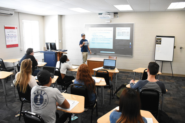 students around classroom tables with professor