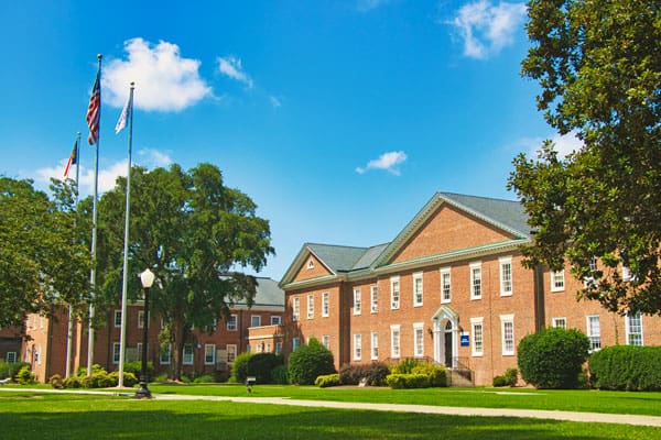 Front lawn view of Braswell with three flags. 
