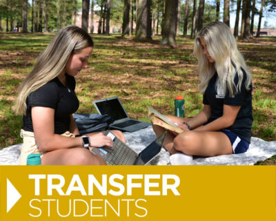 two white female students studying on lawn