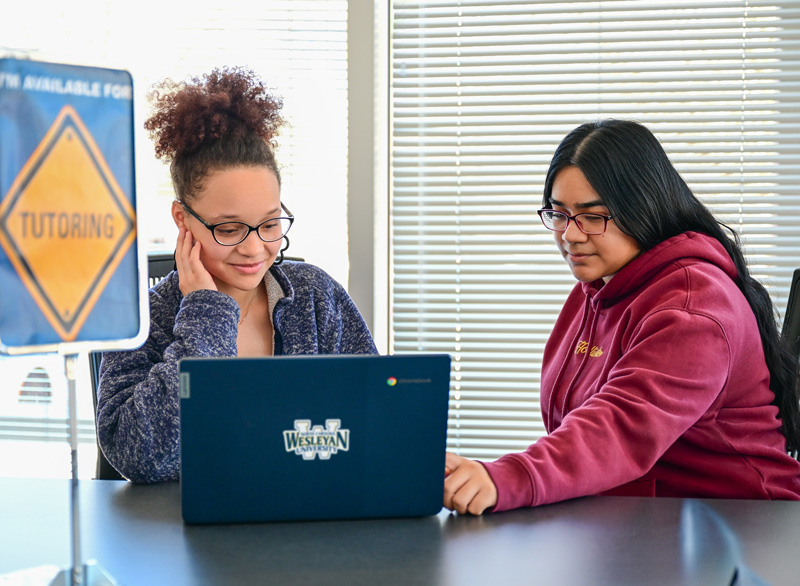 students tutoring one another in front of computer